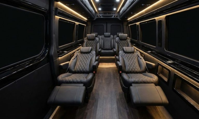 Jet Sprinter VIP cabin interior with seven reclining black diamond-quilted leather captain chairs, warm ambient lighting, and a hardwood-style floor