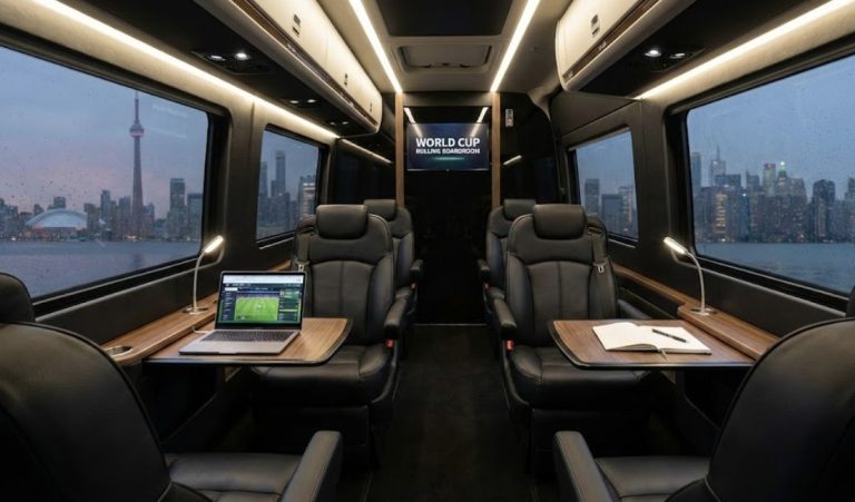Executive Sprinter cabin interior arranged as a rolling boardroom with open work tables, a laptop, and notebooks