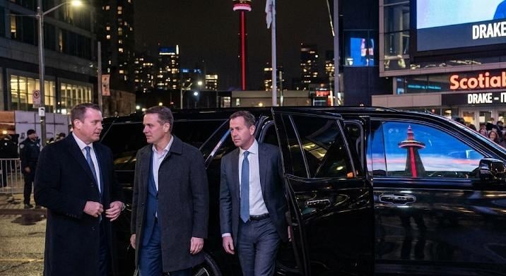 Black Mercedes-Benz Sprinter pulled to the portico of a downtown Toronto convention centre with business travelers boarding