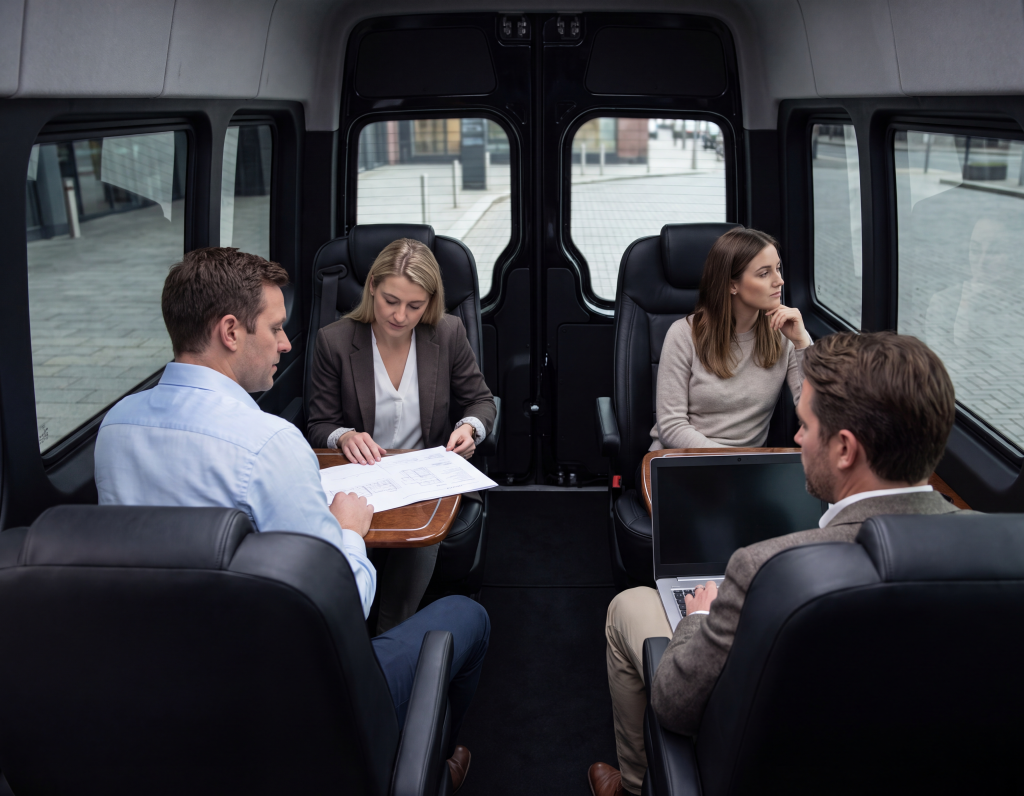 Four executives working at a fold-out table inside the cabin of a black Sprinter during a daytime booking