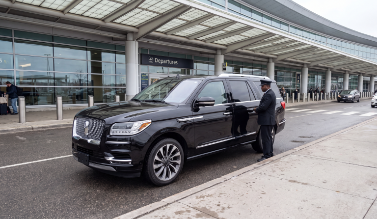 Black Lincoln Navigator at the Toronto Pearson departures kerb, uniformed chauffeur at the rear door