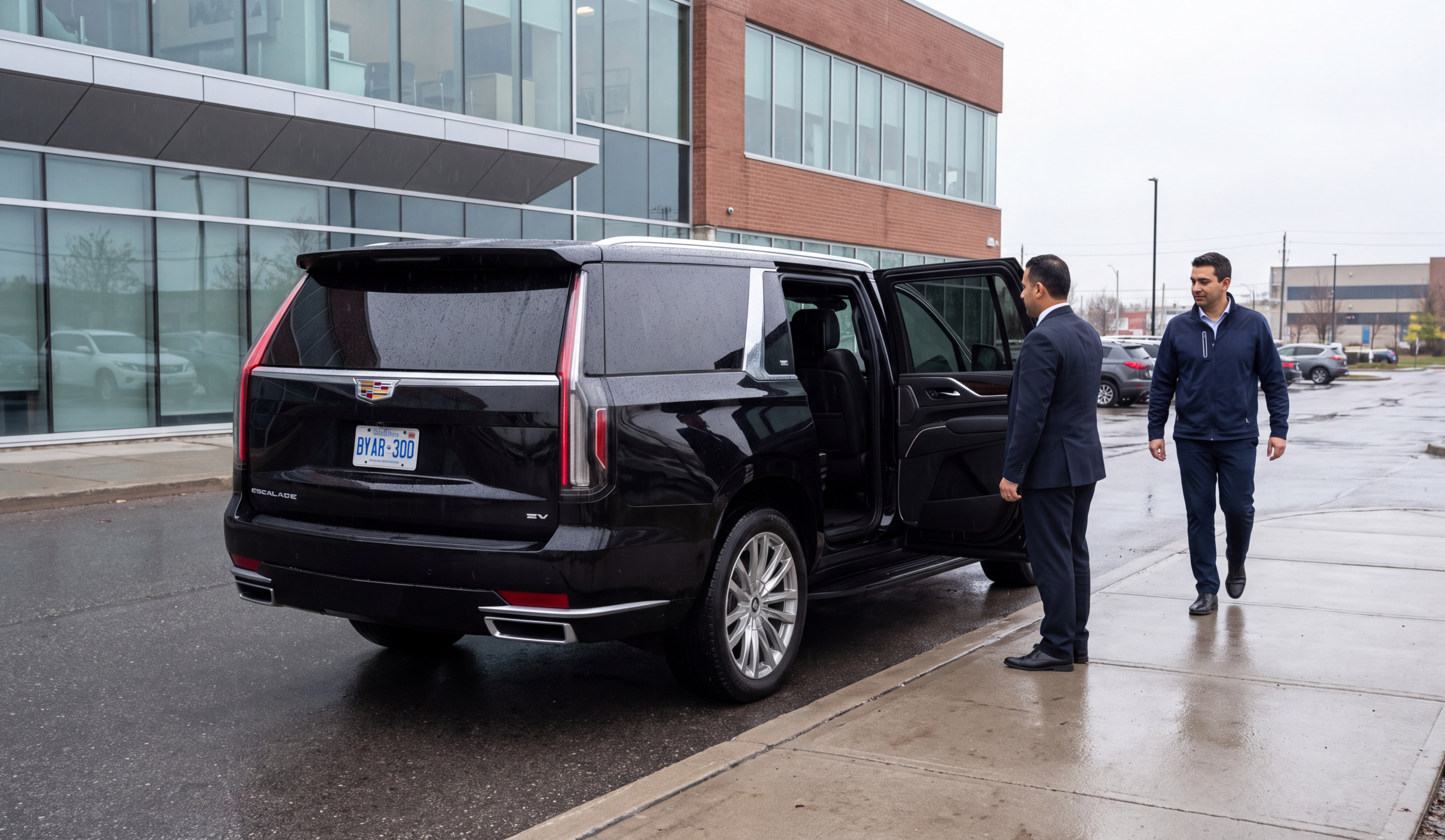Chauffeuropolis chauffeur holding the rear door of a black car at the kerb for an arriving passenger, physio clinic kerb